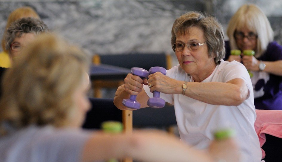 Older women in a group fitness class lifting small hand weights