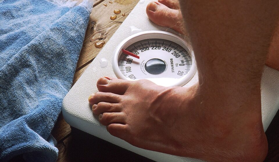GLP-1 Drugs and Medicare in 2026: The $50 GLP-1 Bridge, Who Qualifies, and What Part D Still Covers A person standing barefoot on a bathroom scale