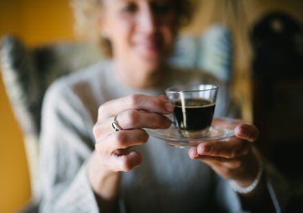 Smiling senior woman holding a glass of espresso coffee closeup