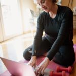 Older woman with light dumbbells on an exercise mat at home