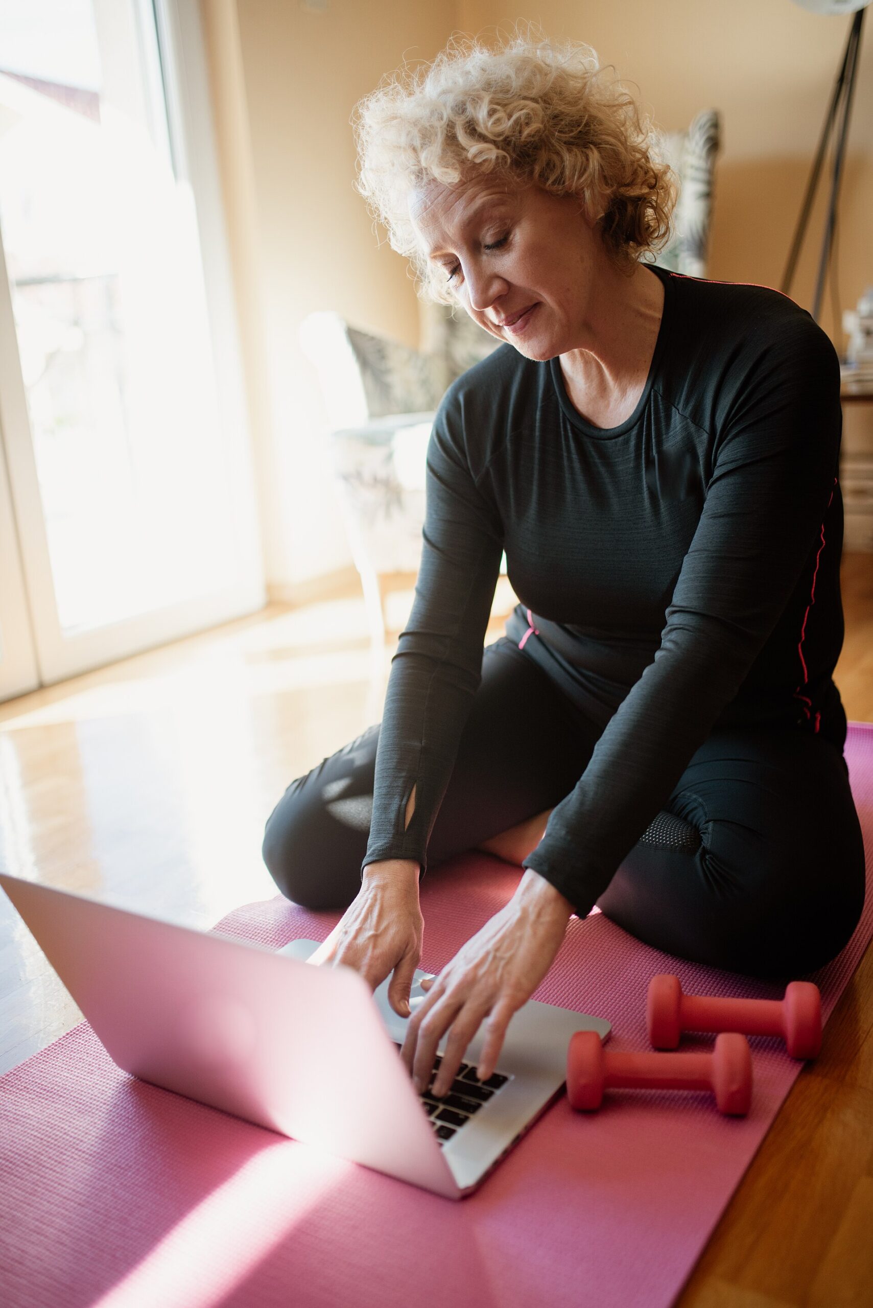 Older woman with light dumbbells on an exercise mat at home