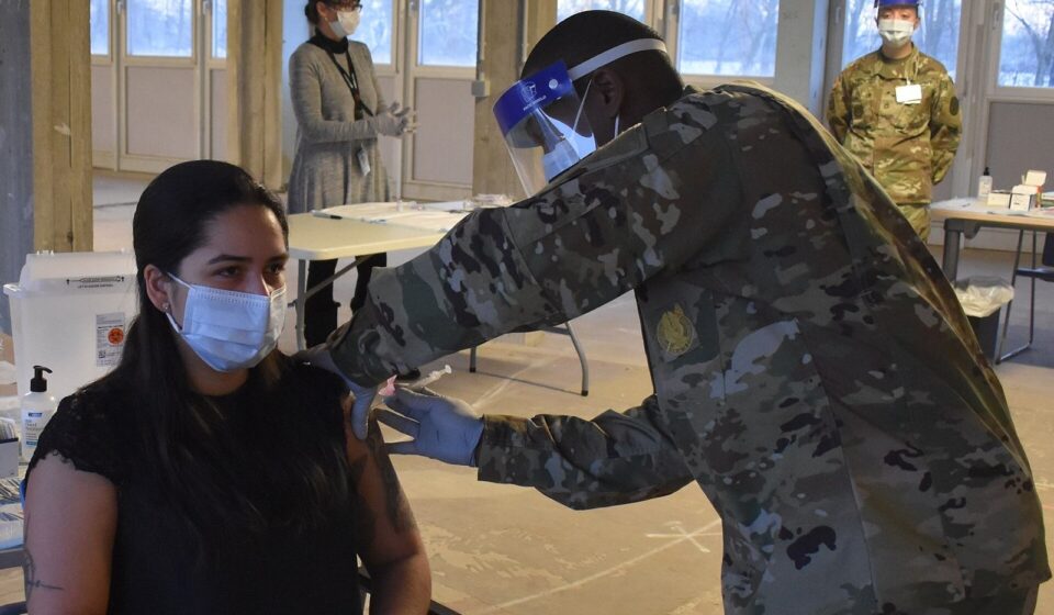 A health worker giving a vaccine in the upper arm at a vaccination clinic