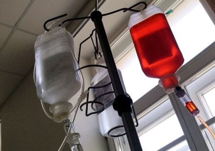 Infusion bags of chemotherapy drugs hanging from an IV pole next to a window