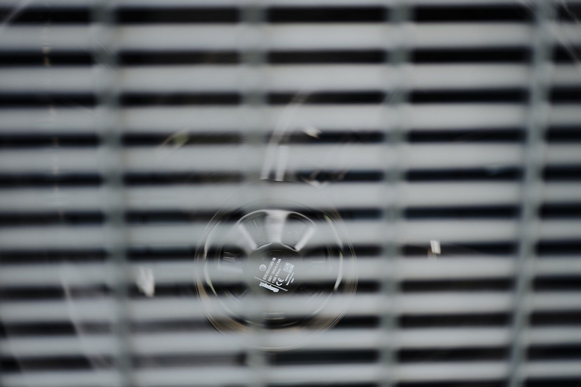 Close-up of an electric fan behind window blinds