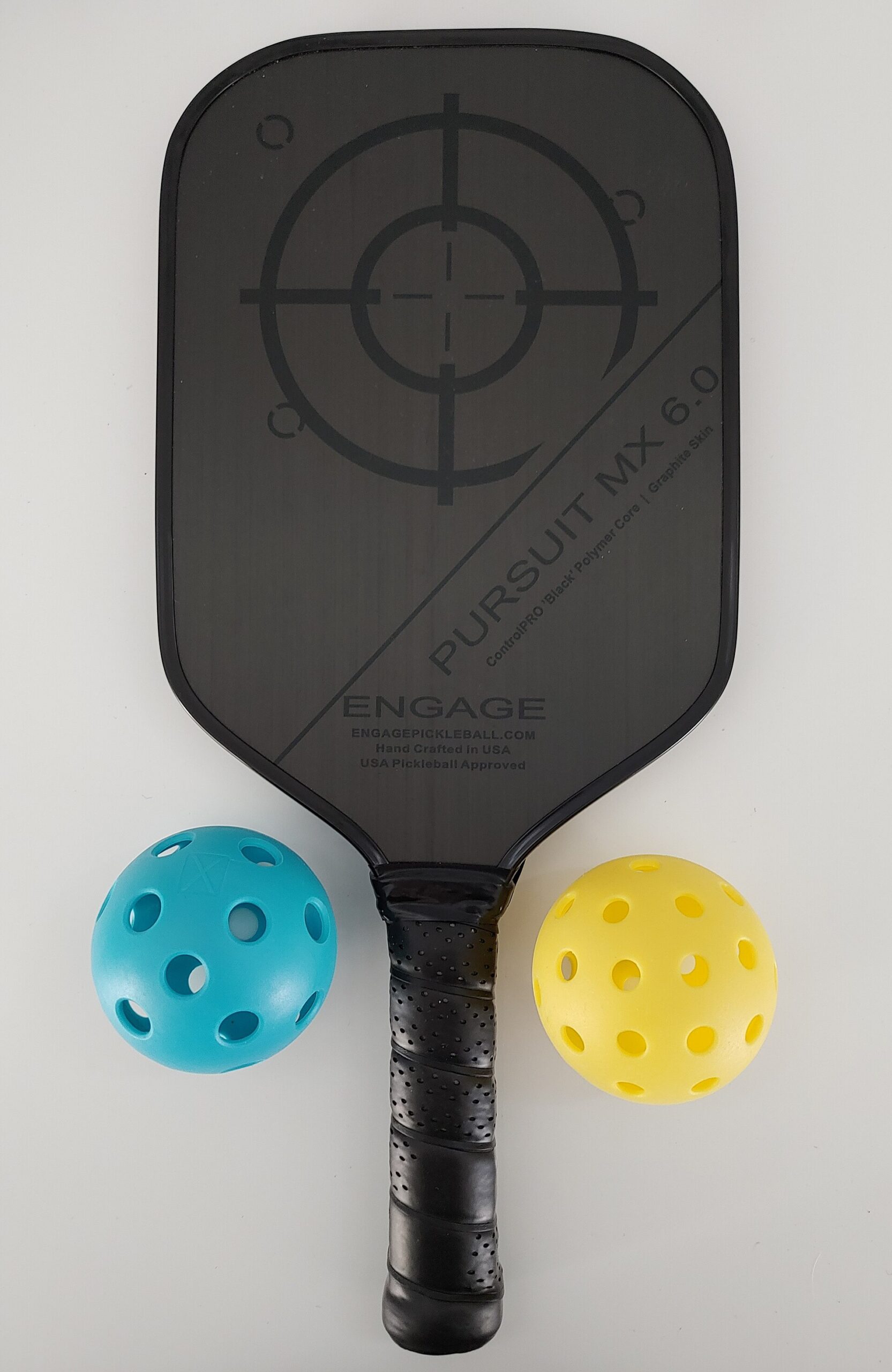 A pickleball paddle with one blue indoor-style ball and one yellow outdoor ball