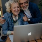 Smiling senior couple looking at a laptop together at a wooden table
