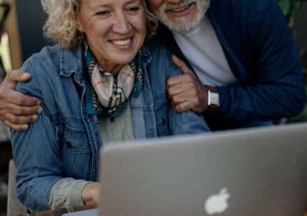 Smiling senior couple looking at a laptop together at a wooden table
