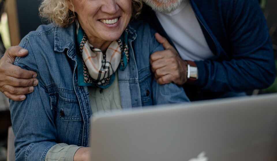 Medicare Open Enrollment for 2027 Coverage: Dates, Deadlines and What to Compare Smiling senior couple looking at a laptop together at a wooden table