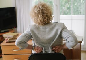 An older woman holding her lower back in pain at home