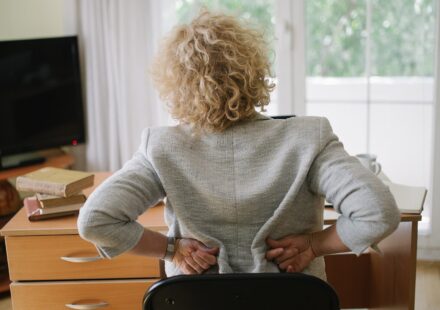 An older woman holding her lower back in pain at home
