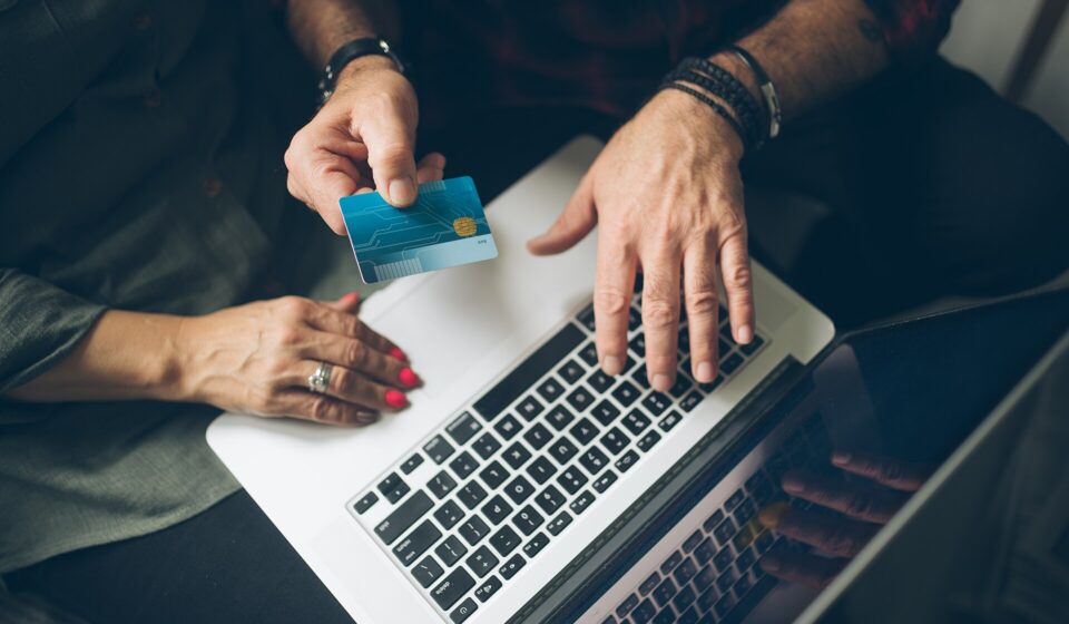 Senior couple at home checking finance on credit card from above