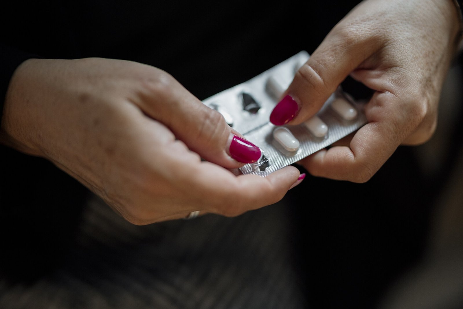 Close-up of hands opening a blister pack of pills at home
