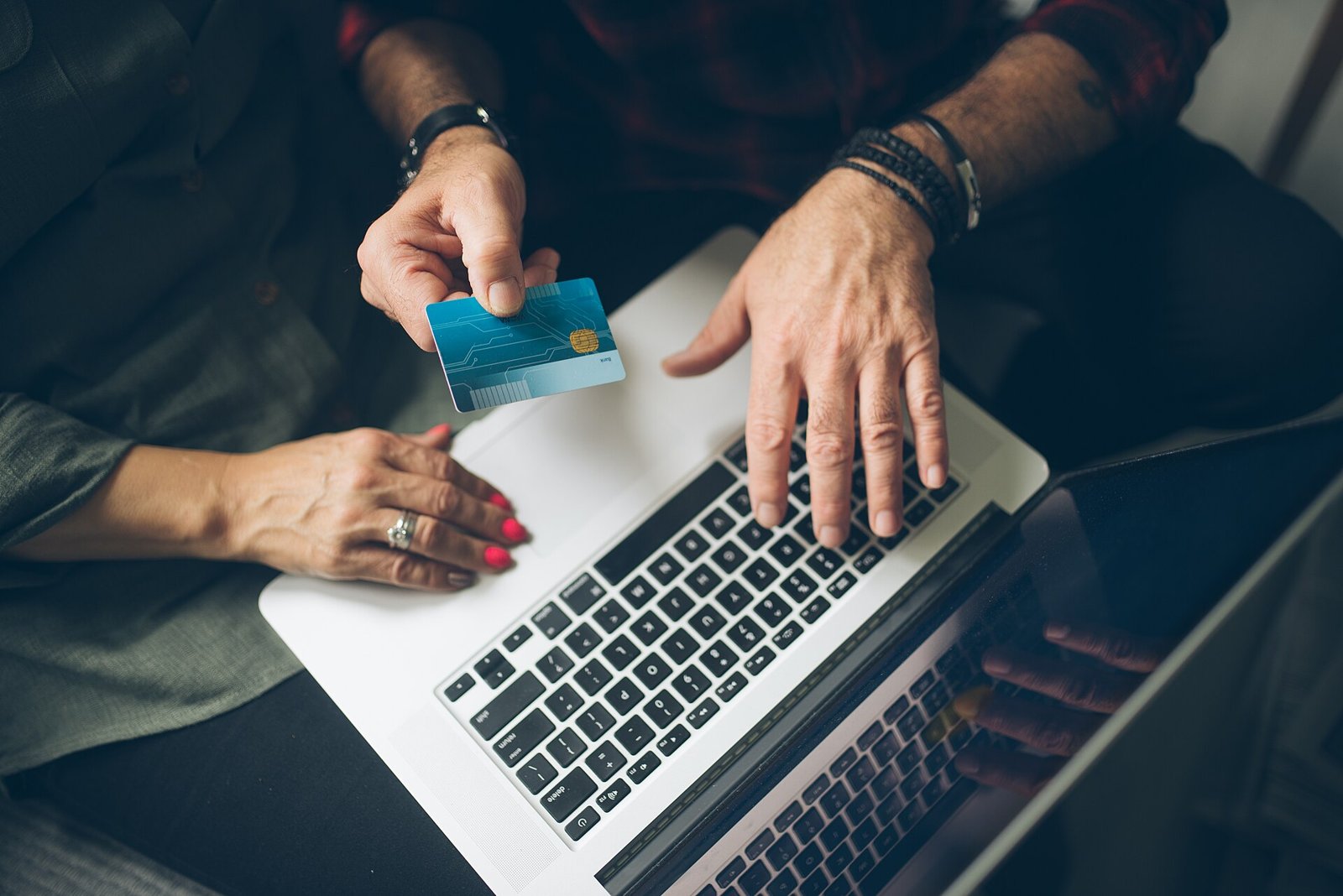 Older couple at a laptop, one holding a payment card while they review bills together