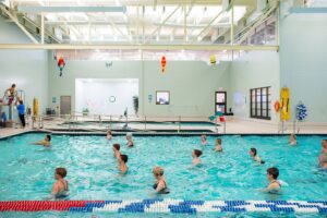 Adults taking a water aerobics class in an indoor pool