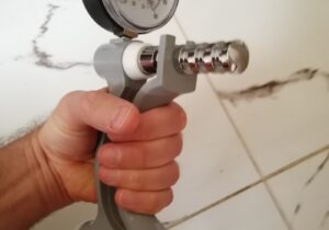 A hand squeezing a hand grip dynamometer that measures grip strength