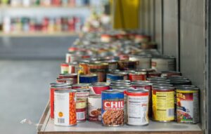 Rows of canned vegetables, soups and beans on a food bank shelf