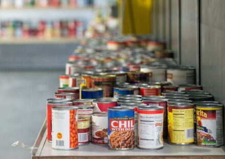 Rows of canned vegetables, soups and beans on a food bank shelf