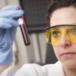 Lab technician holding up a blood sample tube to check it