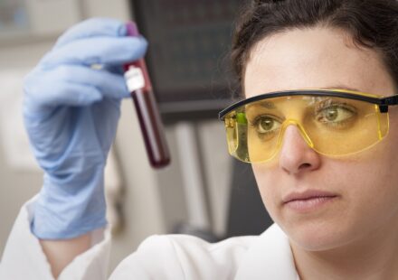Lab technician holding up a blood sample tube to check it