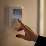A hand adjusting the temperature on a home thermostat
