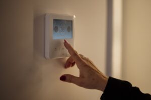 A hand adjusting the temperature on a home thermostat