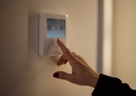 A hand adjusting the temperature on a home thermostat