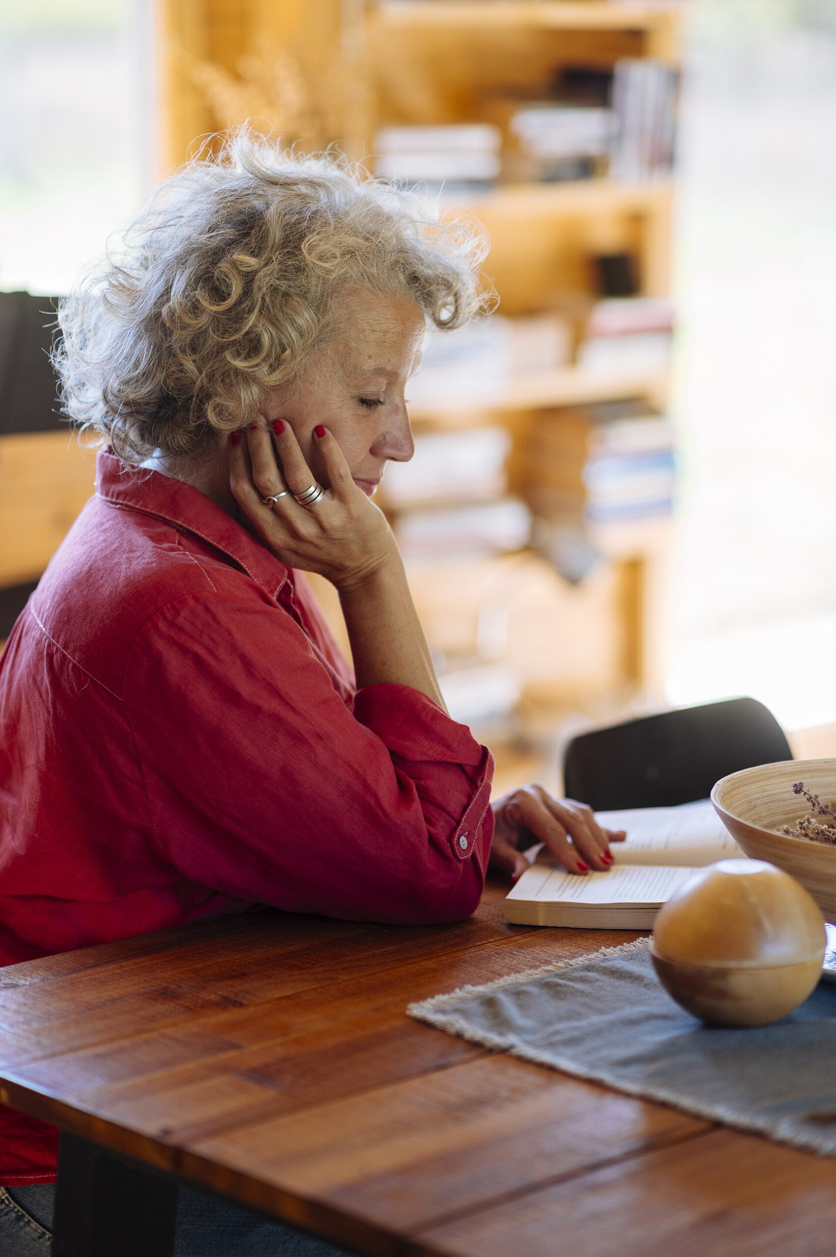 Older woman reading at a wooden table at home