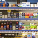 Shelves of over-the-counter pain relievers and cold medicines in a grocery store pharmacy aisle