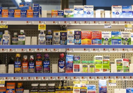 Shelves of over-the-counter pain relievers and cold medicines in a grocery store pharmacy aisle