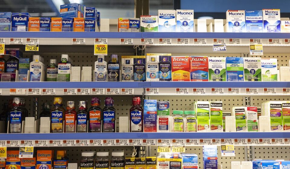 Shelves of over-the-counter pain relievers and cold medicines in a grocery store pharmacy aisle