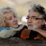 Senior couple standing close together by a wooden farm fence
