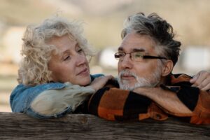 Senior couple standing close together by a wooden farm fence