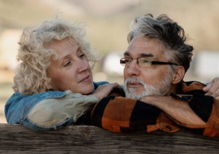 Senior couple standing close together by a wooden farm fence