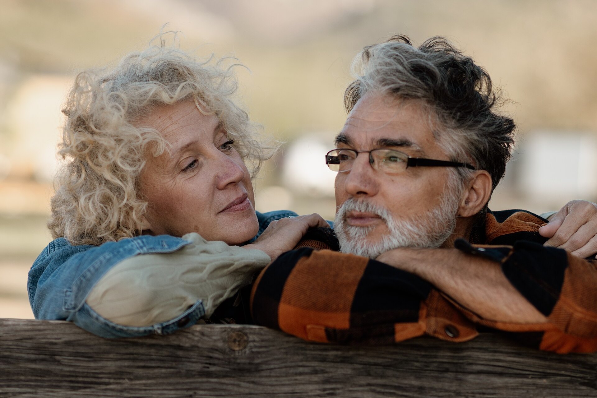 Senior couple standing together by a farm fence