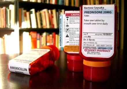 Red prescription bottles with pharmacy labels on a table