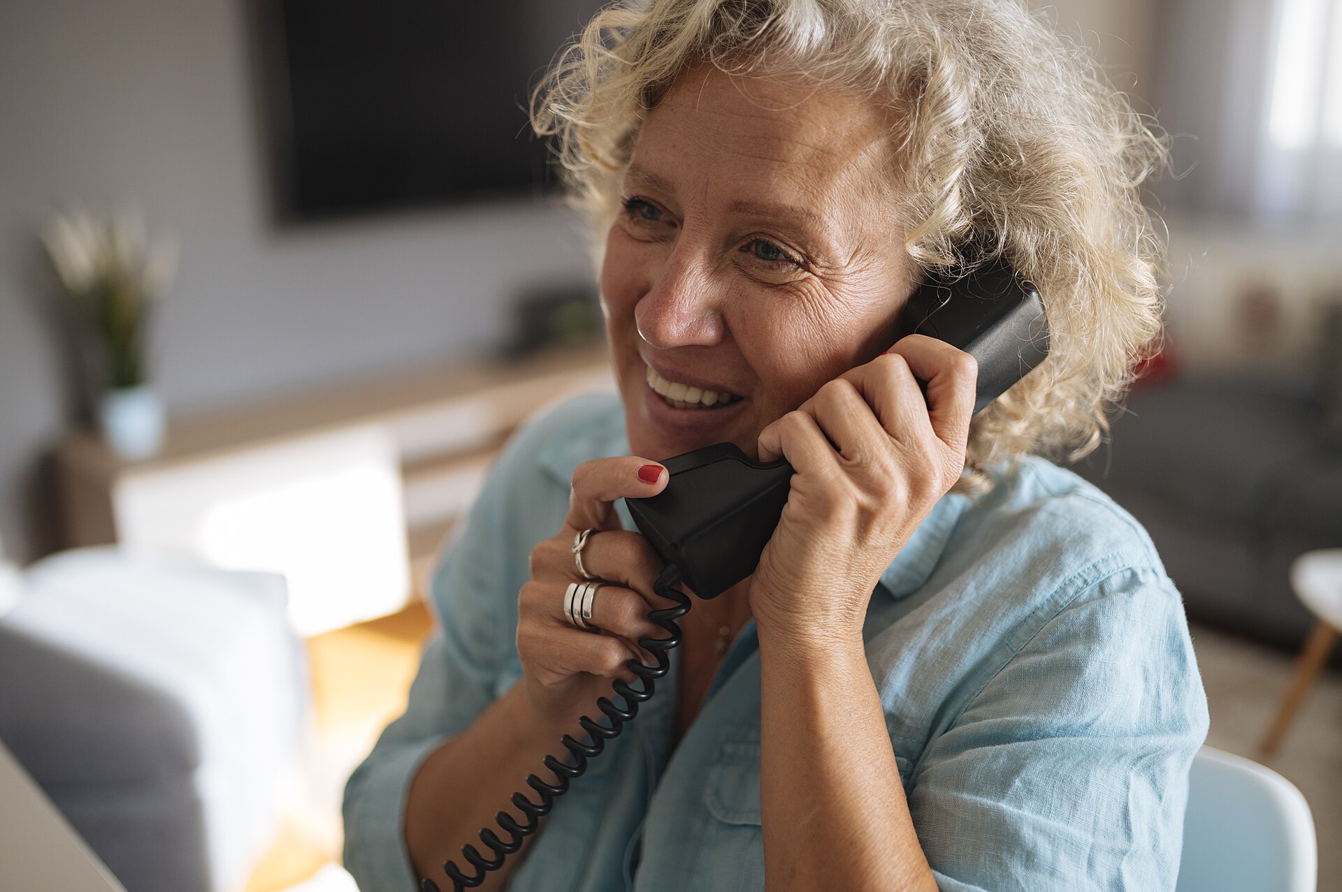 Senior woman smiling while talking on a landline phone at home