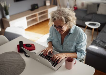 Older woman working on a laptop in a cozy living room