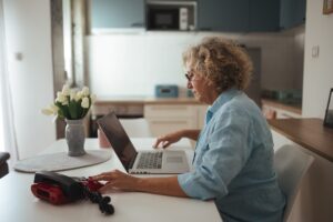 Senior woman working on a laptop at her kitchen table