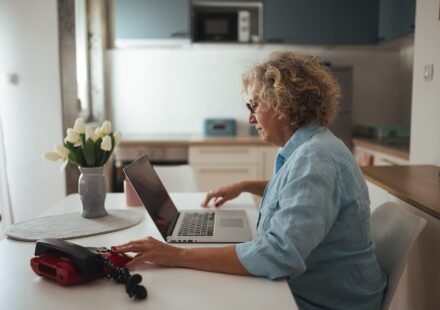 Senior woman working on a laptop at her kitchen table
