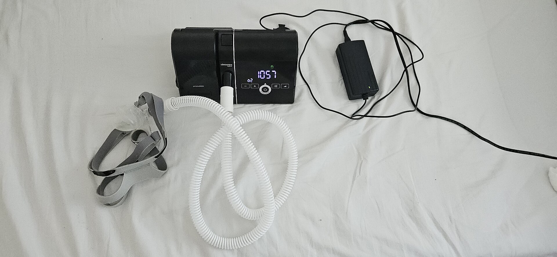 CPAP machine with tubing and a mask on a bed