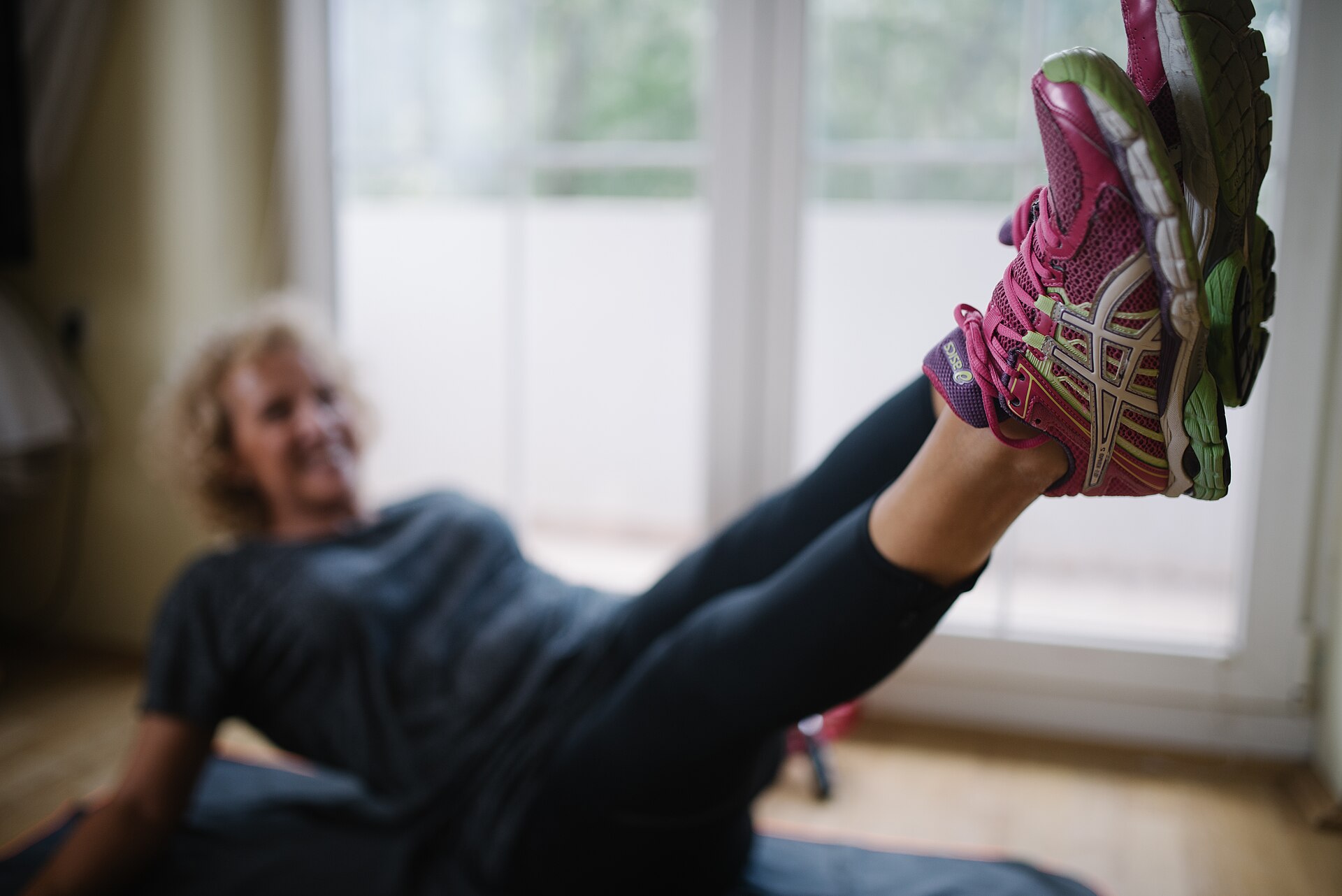 Older woman exercising at home with her sneakers in the foreground