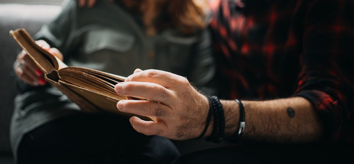 Senior couple sitting on a sofa and reading a book together