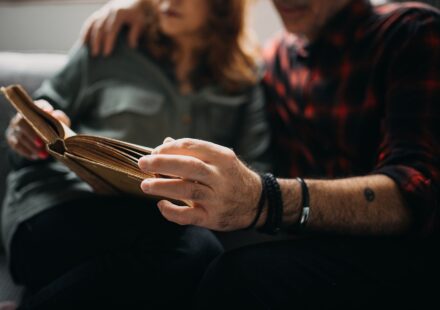 Senior couple sitting on a sofa and reading a book together