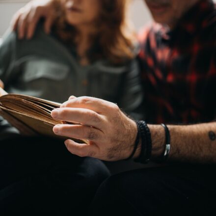 Senior couple sitting on a sofa and reading a book together