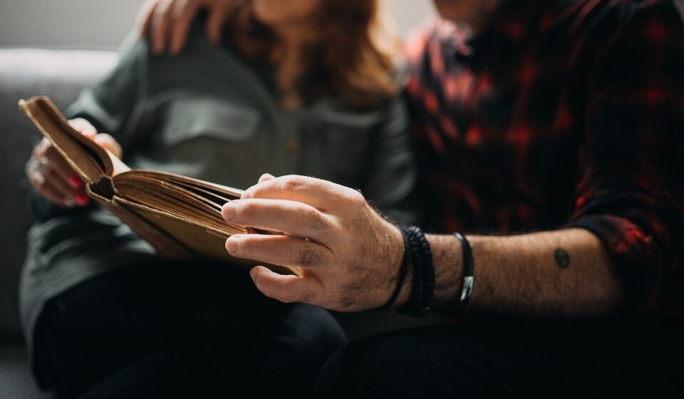 Senior couple sitting on a sofa and reading a book together