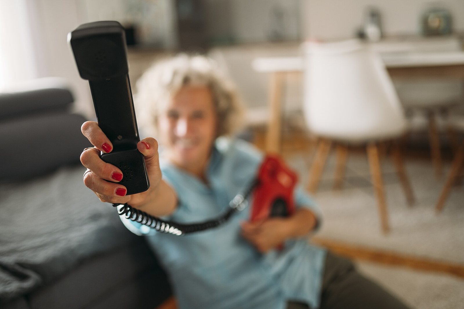 Senior woman smiling and holding a corded phone handset